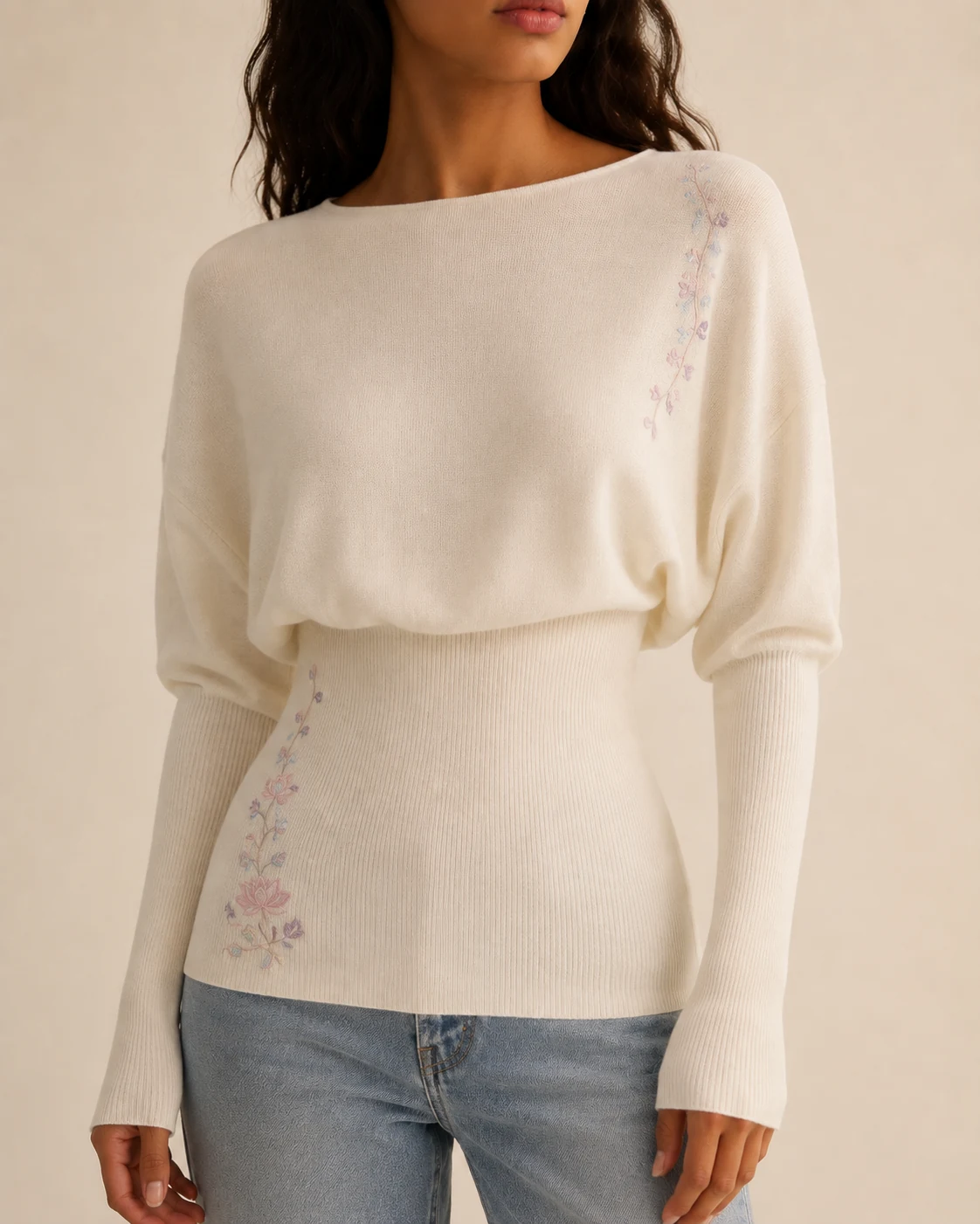 Close view of pastel floral embroidery on an ivory sculpted knit